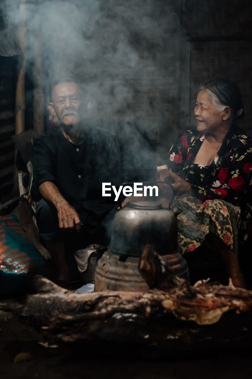 Man and woman preparing food on fire