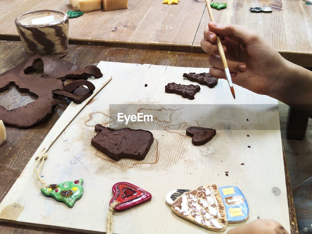 High angle view of man preparing ceramic toy on table