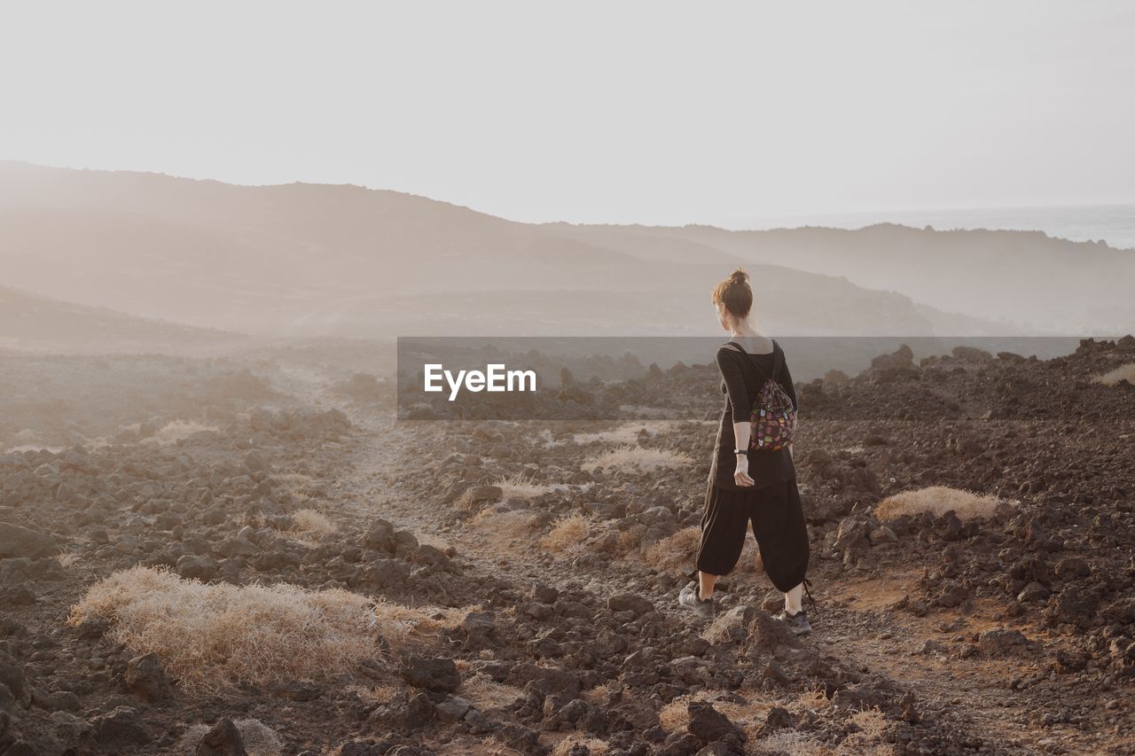 Rear view of woman looking at mountains against sky