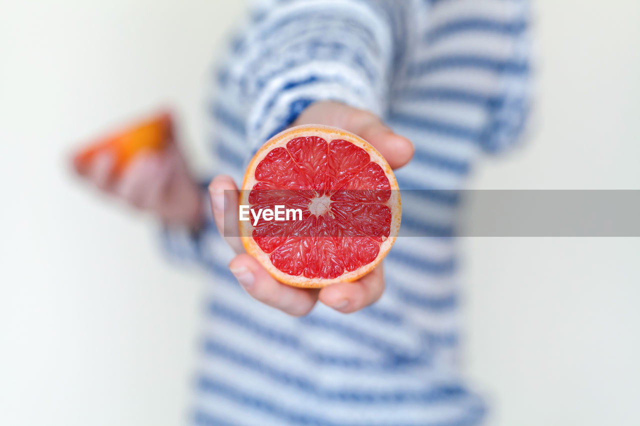 Juicy grapefruit cut on half in hand, healthy eating concept