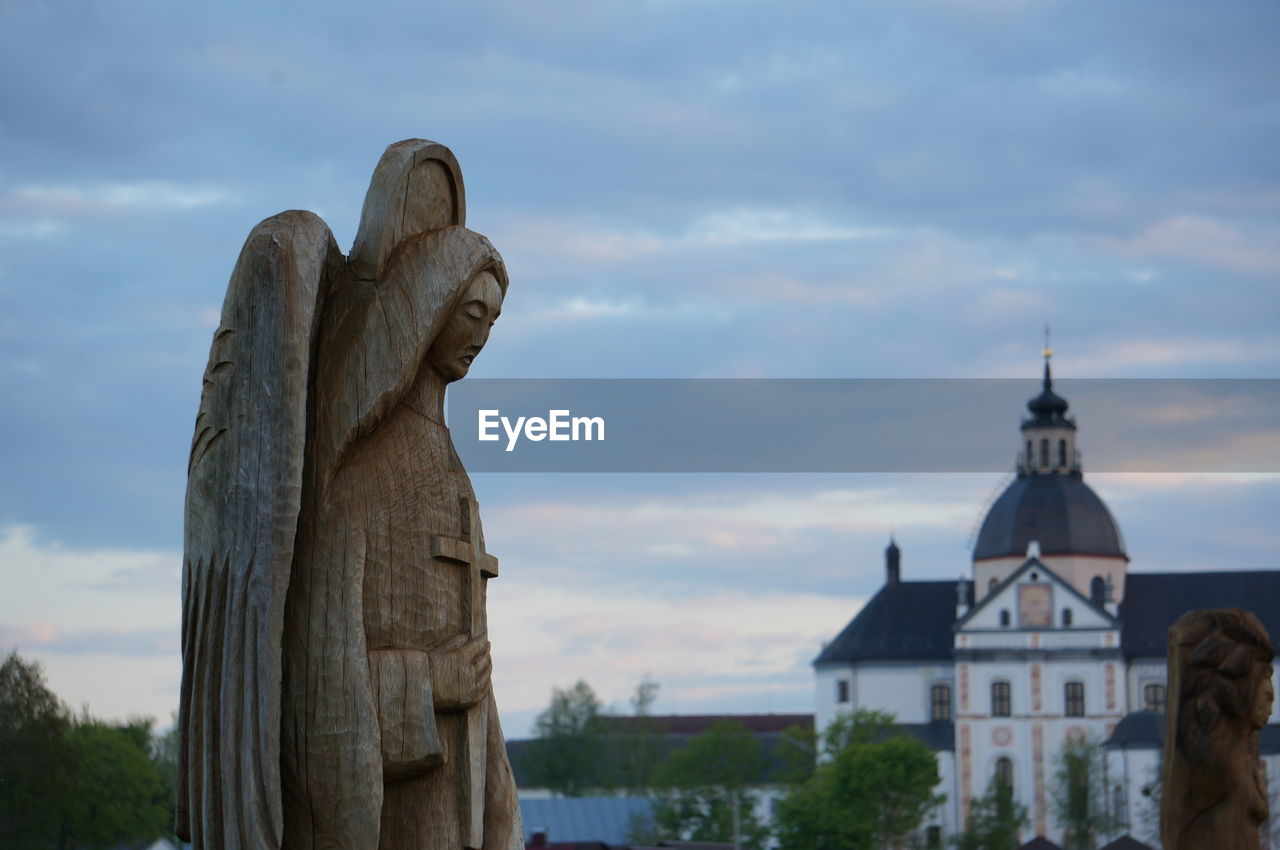 STATUE AGAINST SKY AND BUILDINGS