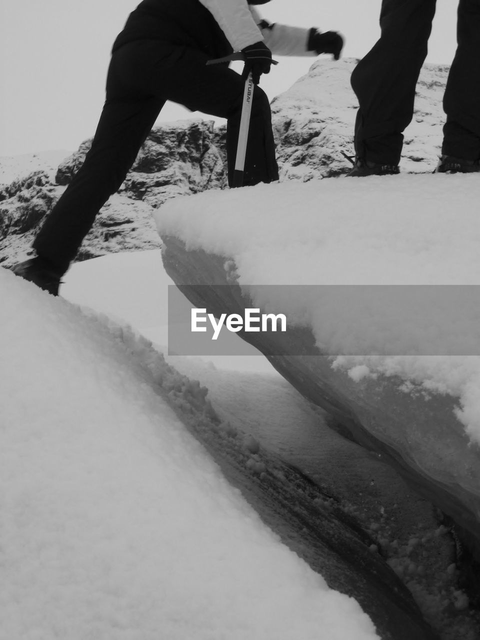 LOW SECTION OF MAN STANDING ON SNOW COVERED MOUNTAIN