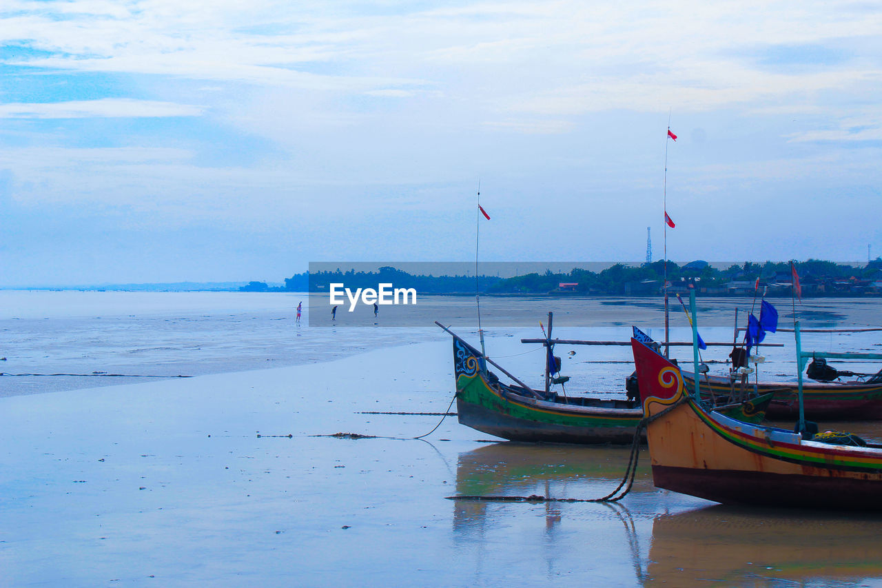 BOAT MOORED ON BEACH AGAINST SKY