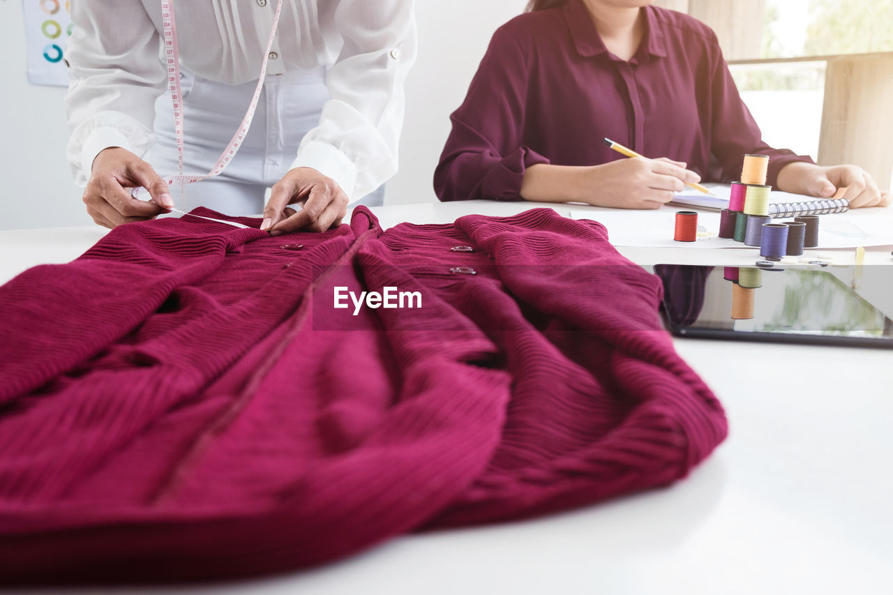 Midsection of fashion designers working on desk