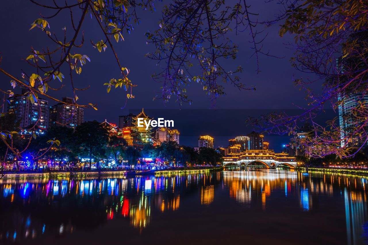 Illuminated buildings by river at night