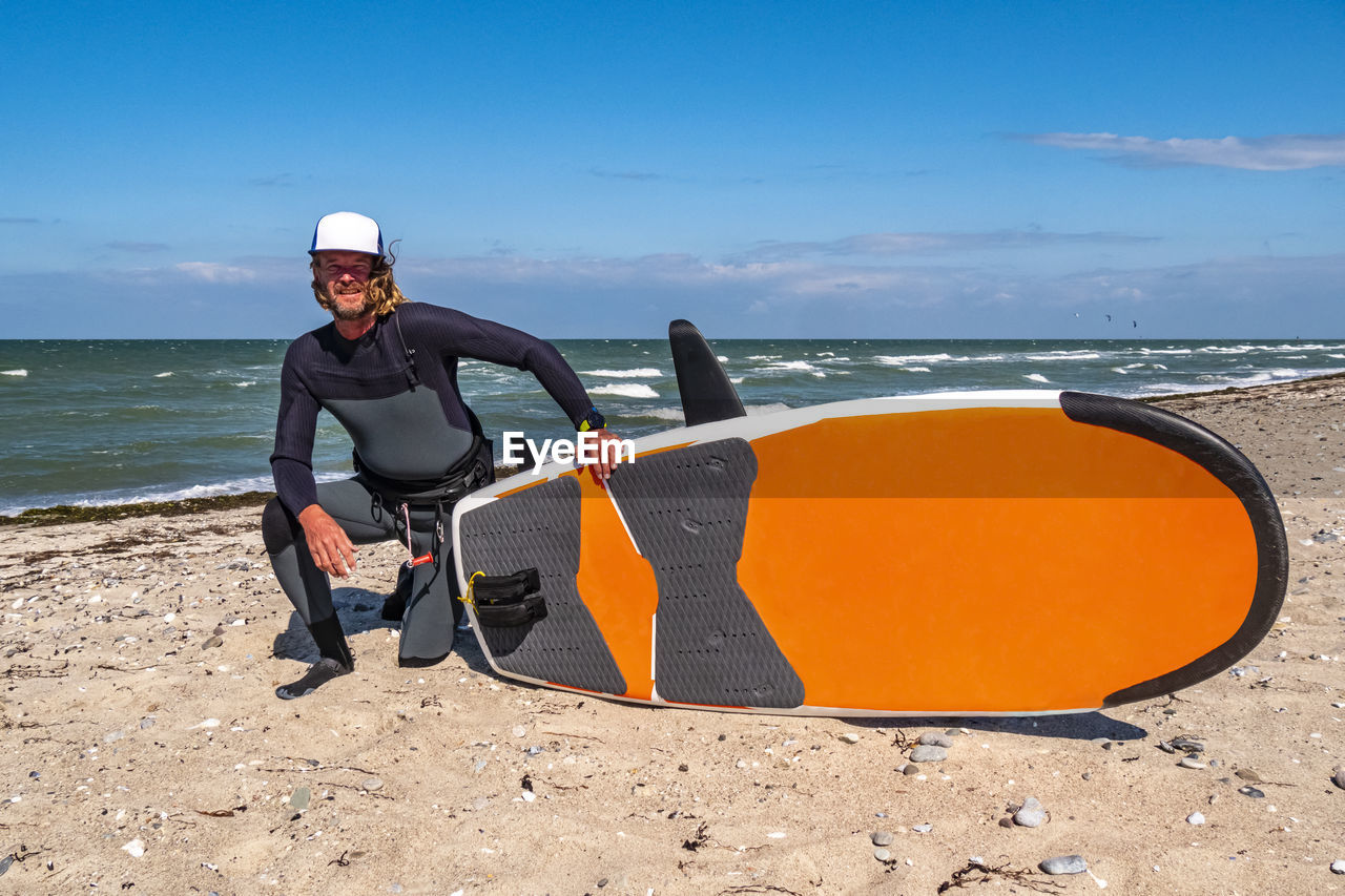 rear view of man sitting on beach against sky