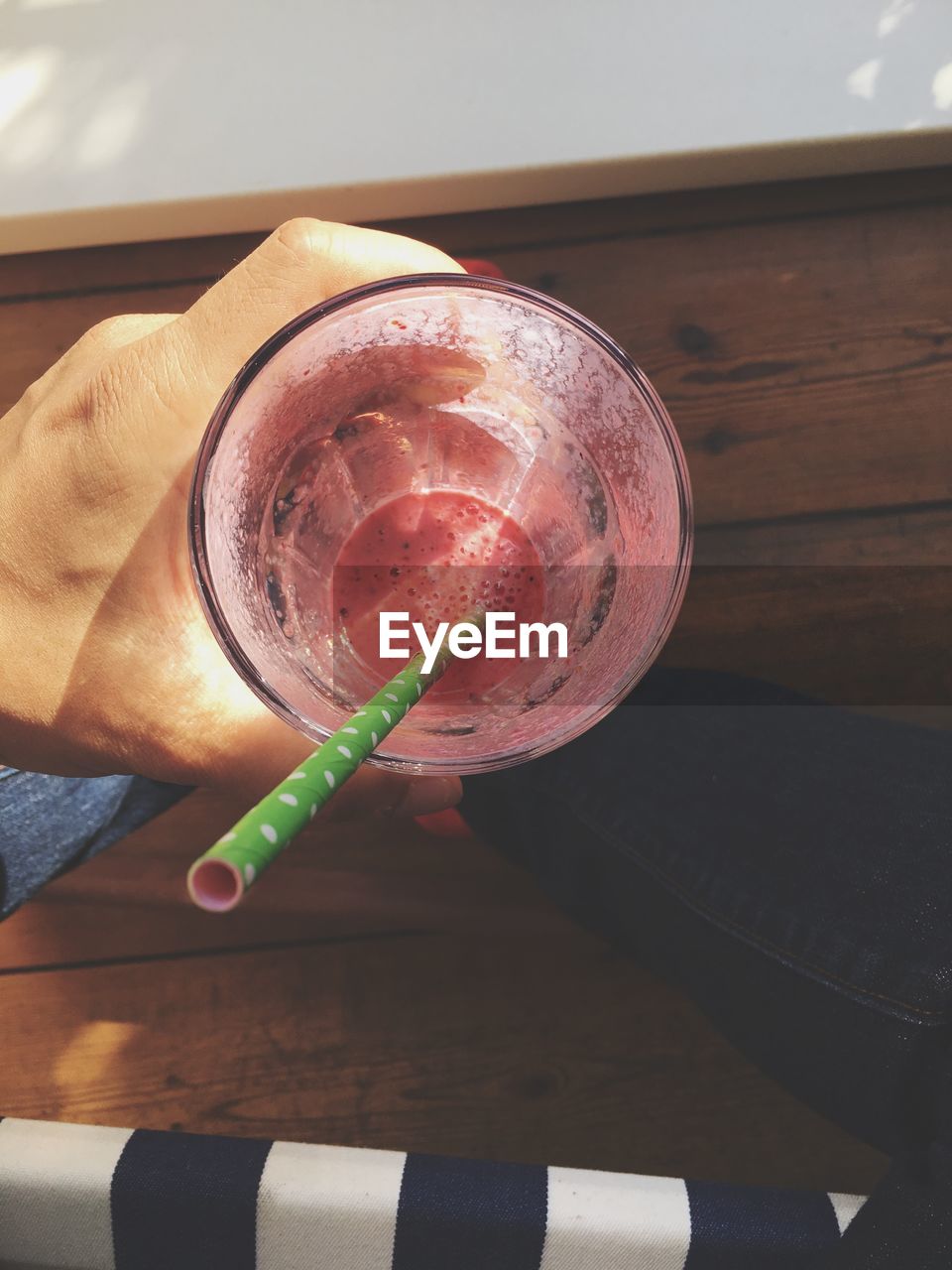 CLOSE-UP OF HAND HOLDING GLASS OF JUICE