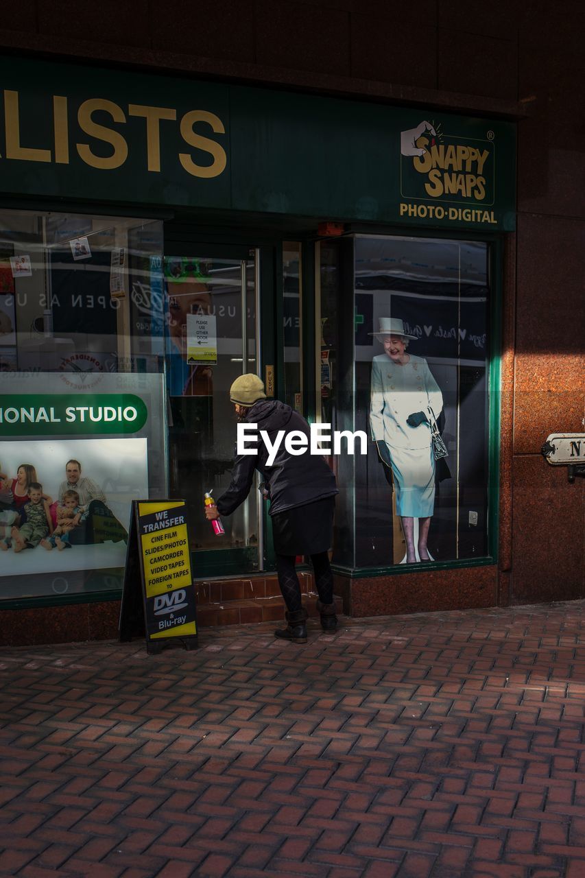 REAR VIEW OF MAN WALKING ON STREET AT STORE