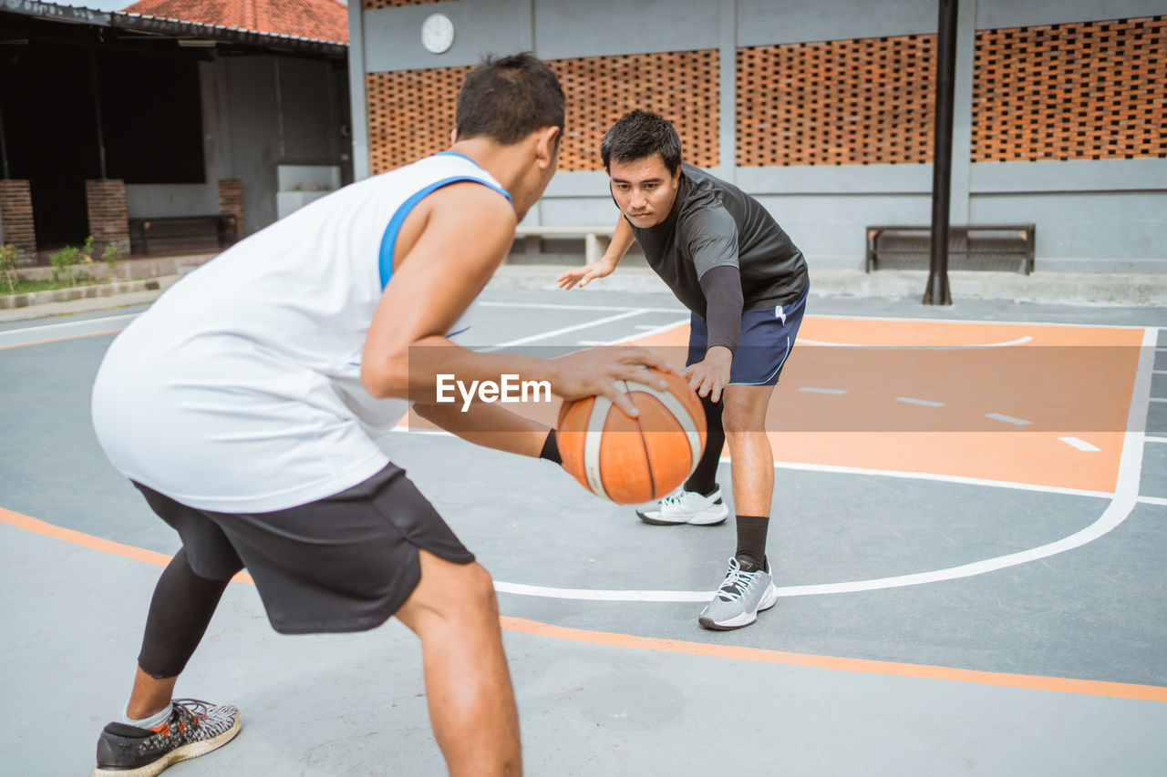 YOUNG MAN PLAYING WITH BALL IN BASKETBALL