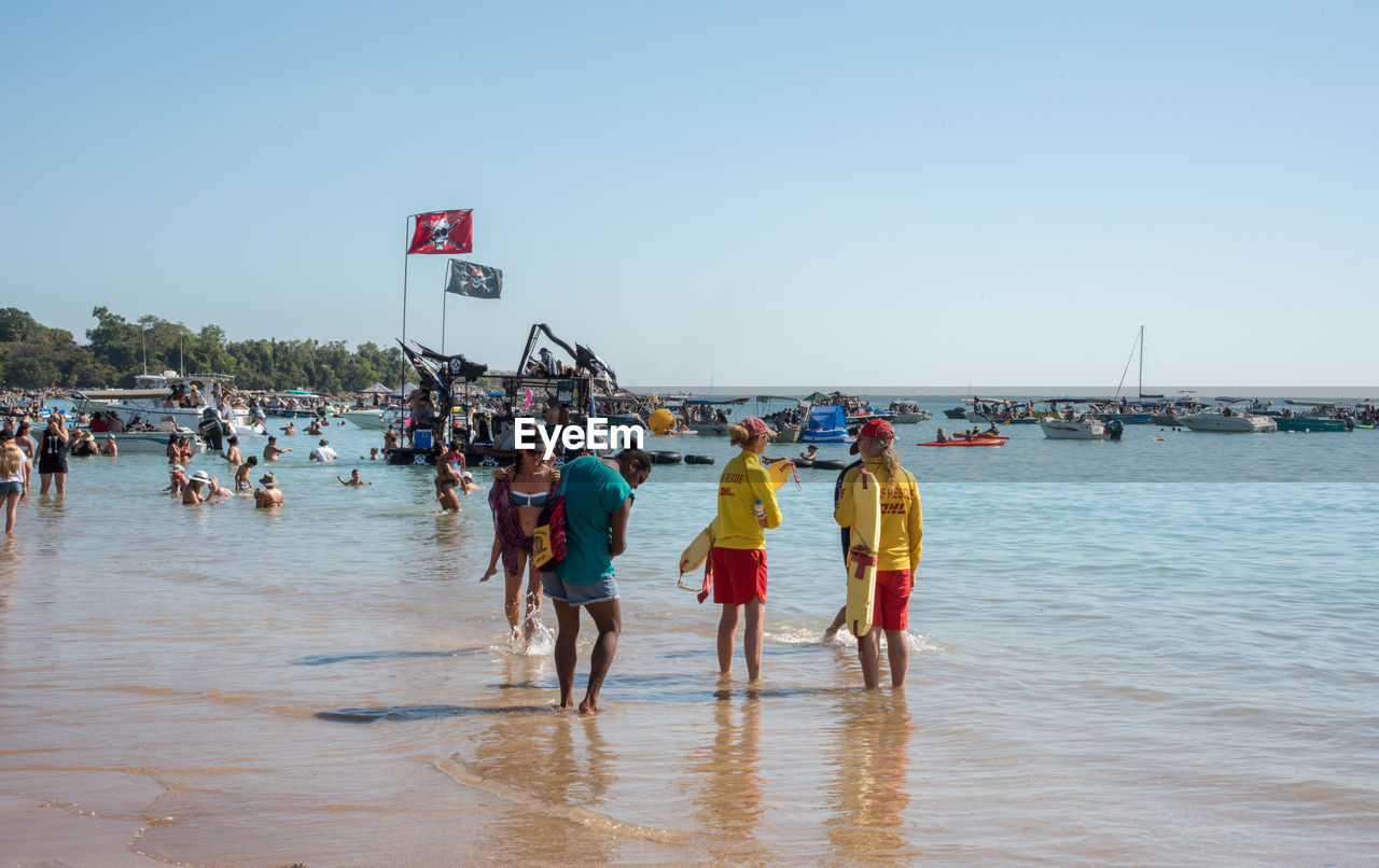 GROUP OF PEOPLE ON BEACH AGAINST CLEAR SKY