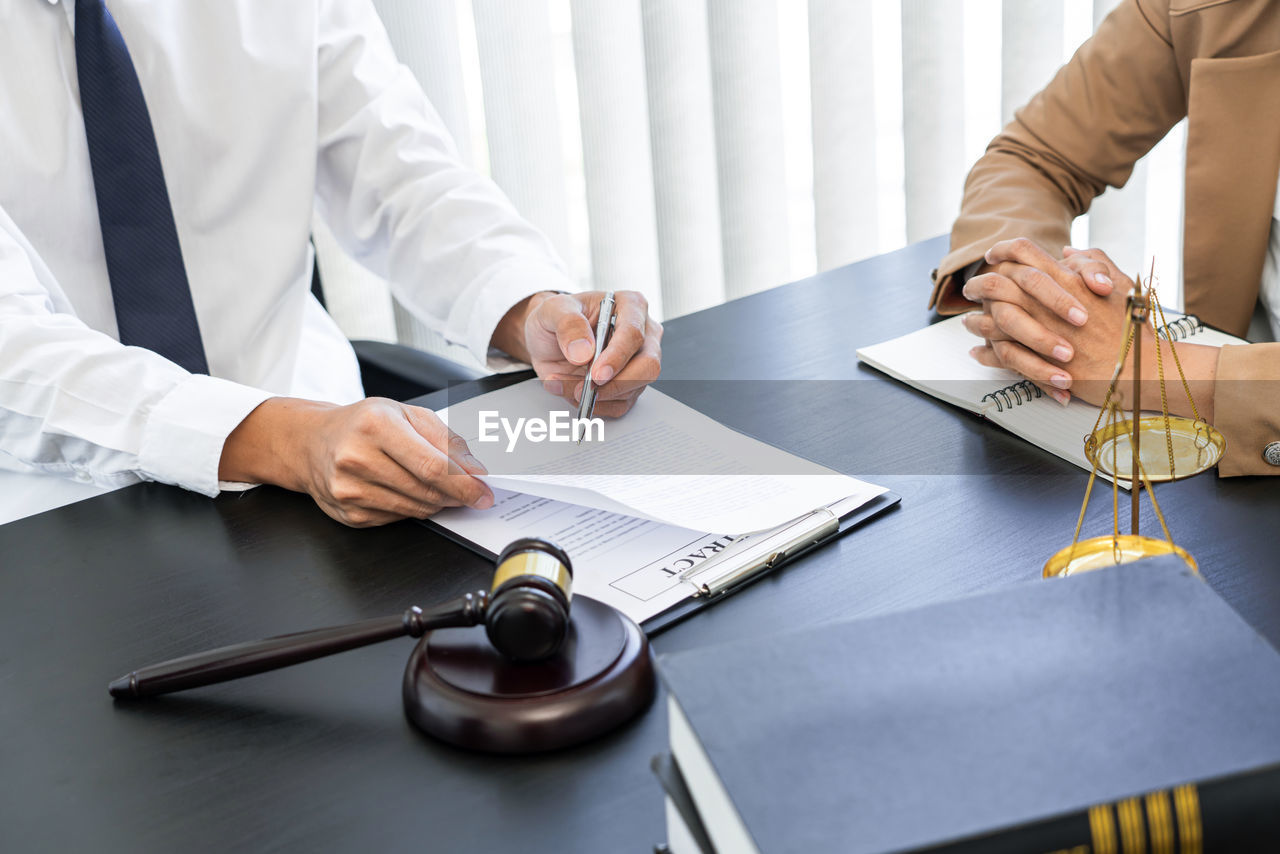 MIDSECTION OF MAN WORKING ON TABLE IN OFFICE