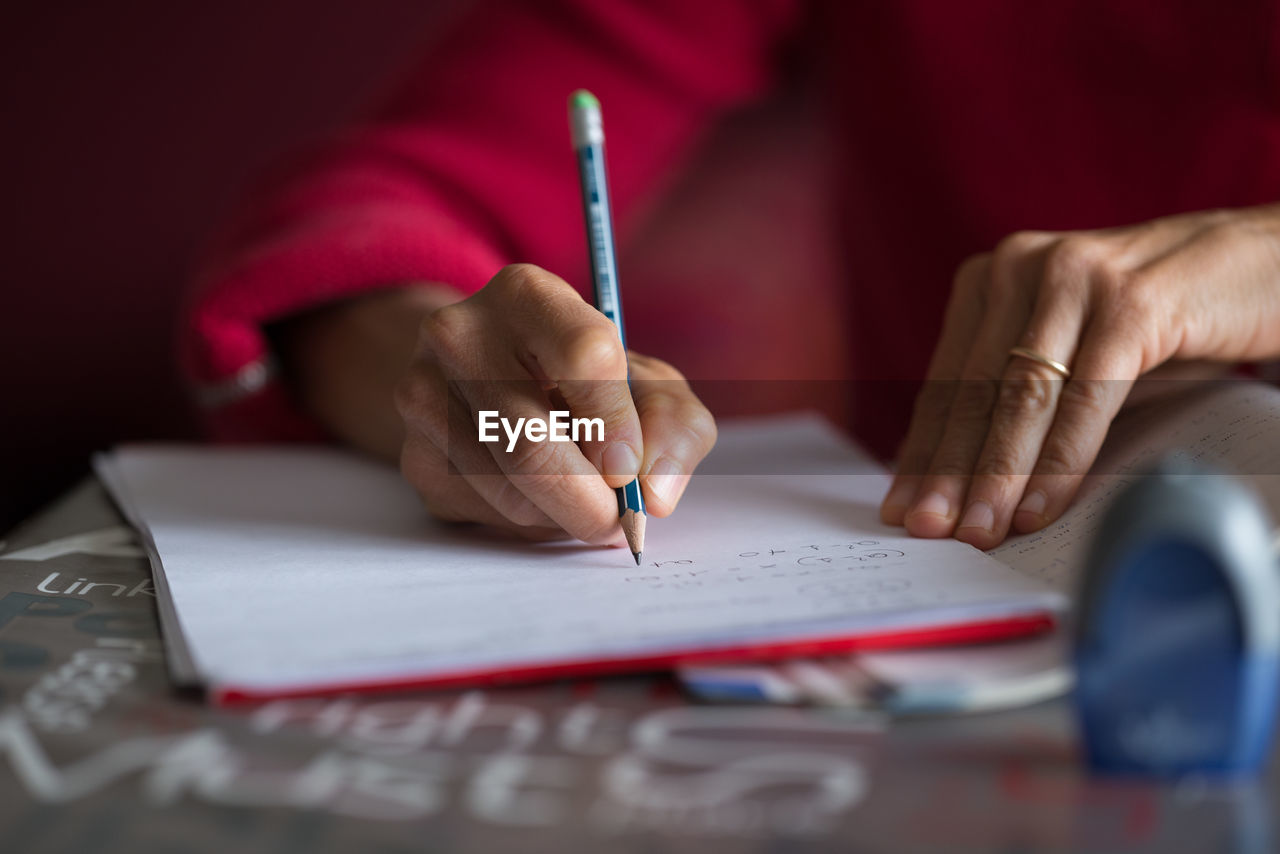 Cropped hands of woman writing in book