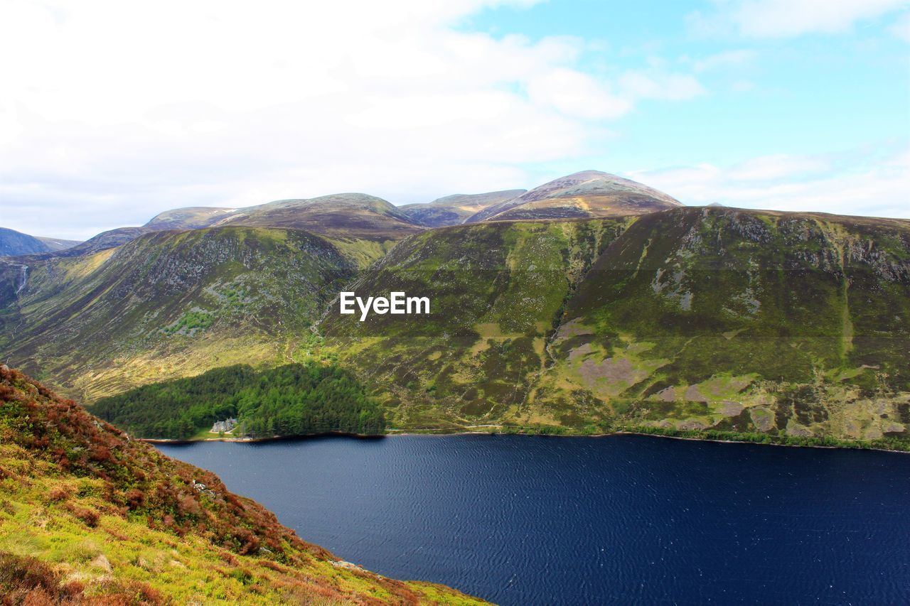 Scenic view of lake by mountains against sky