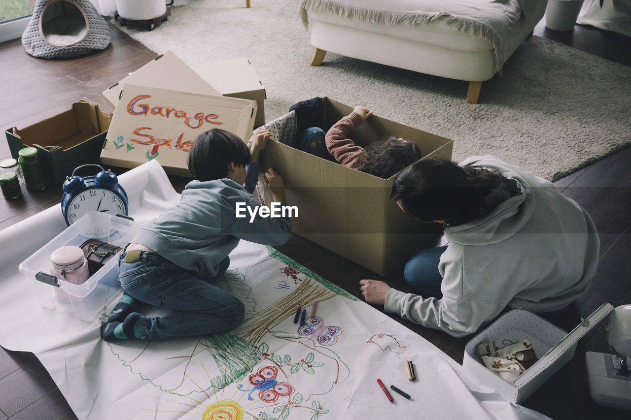 Mother with son drawing on cardboard box in living room at home