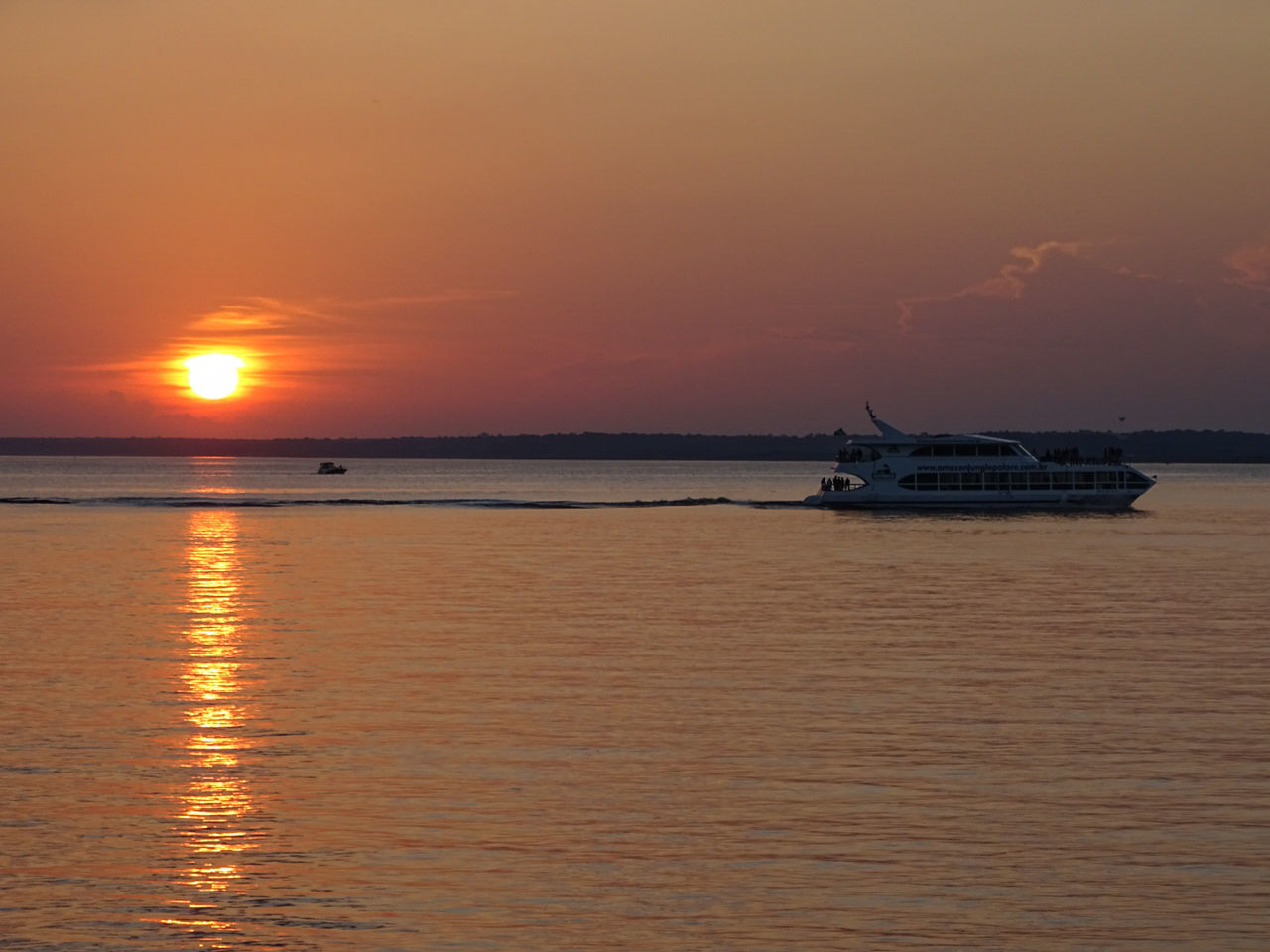 BOAT IN CALM SEA AGAINST ORANGE SKY