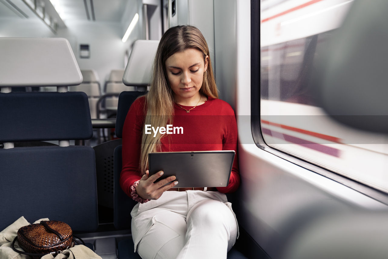 YOUNG WOMAN USING MOBILE PHONE IN BUS