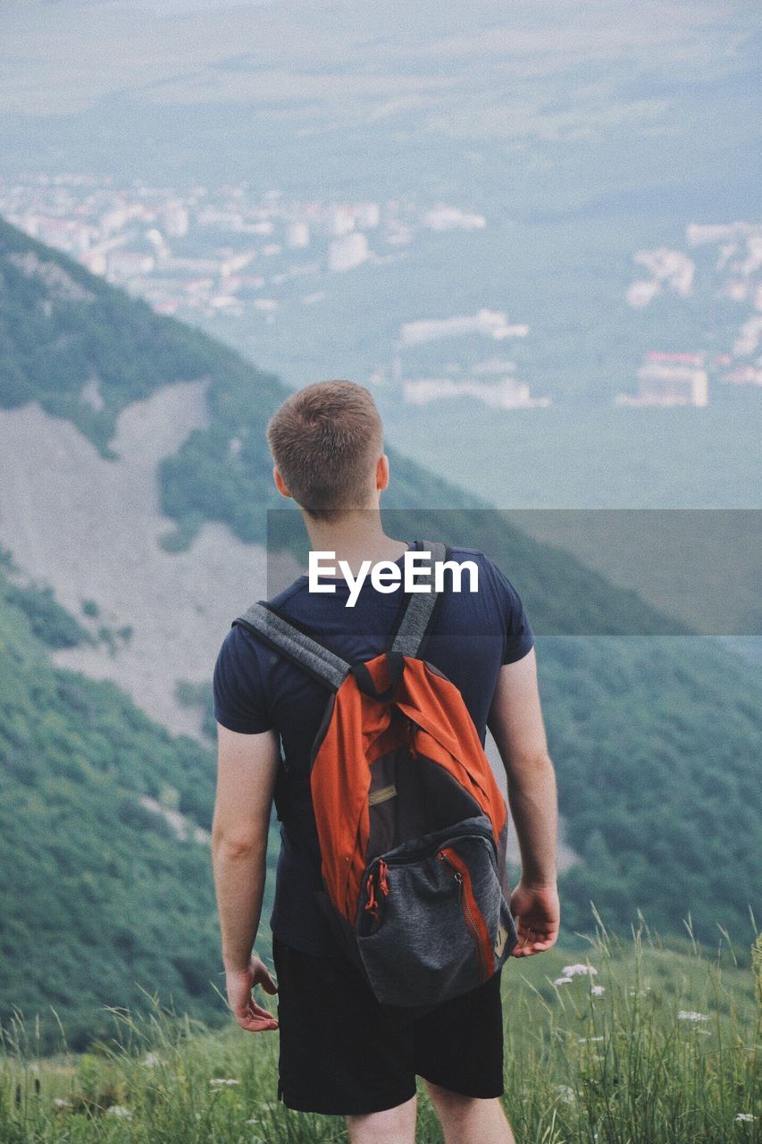 Rear view of man with backpack standing on mountain