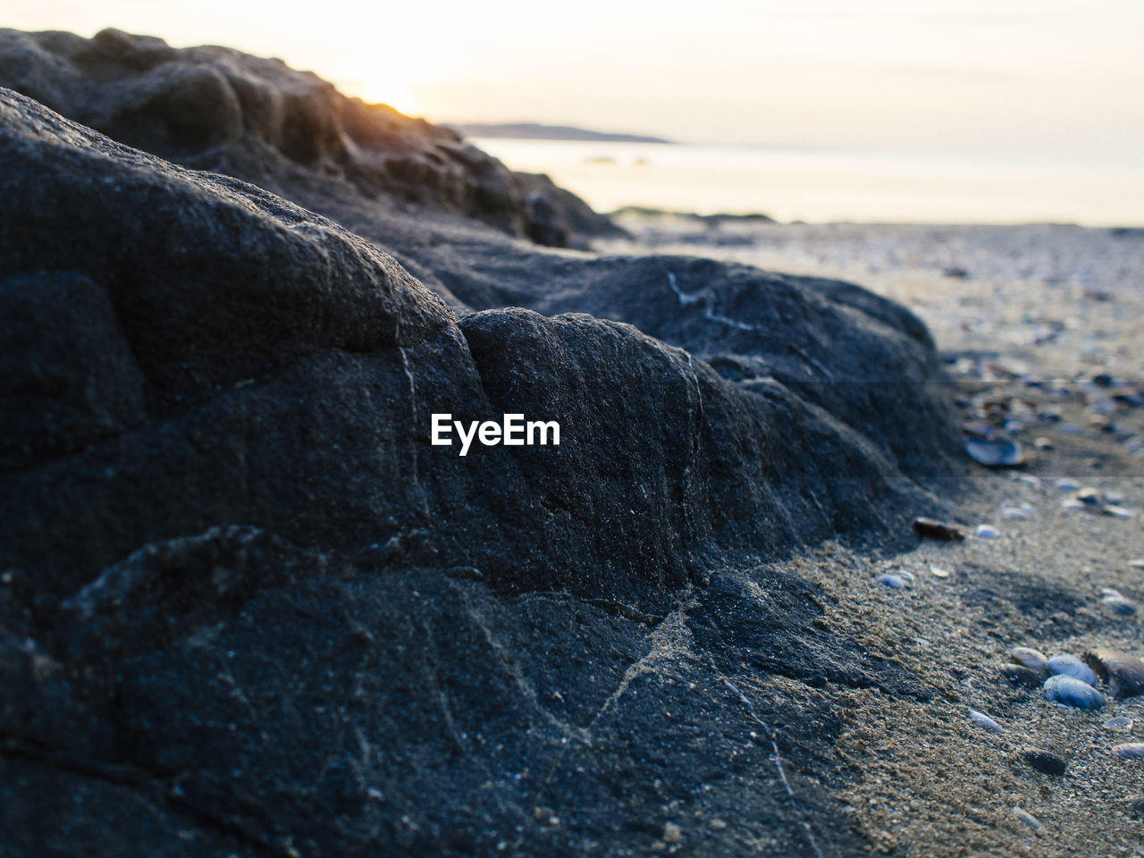CLOSE-UP OF ROCKS ON SHORE AT SUNSET