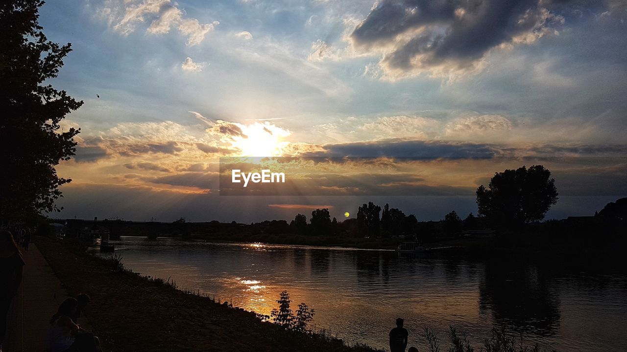 SILHOUETTE TREES BY RIVER AGAINST SKY AT SUNSET