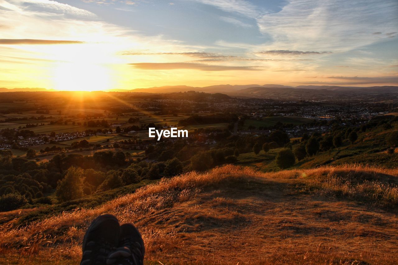 Low section of person against sky during sunset