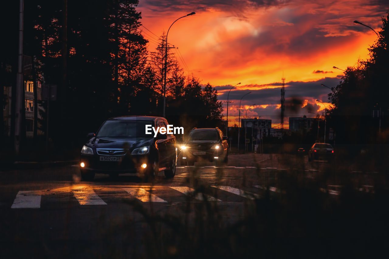 CARS ON ROAD IN CITY AT SUNSET