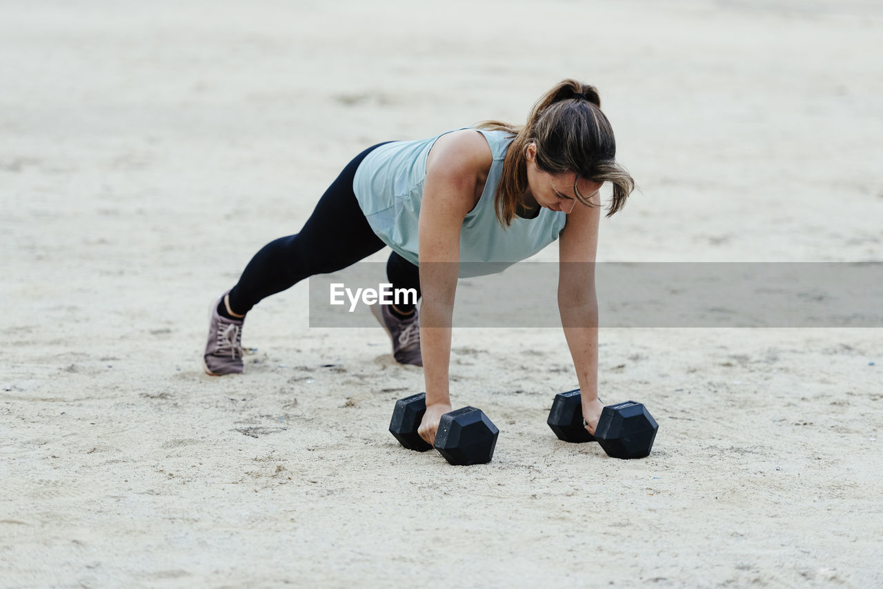 Young woman doing weight training in urban environment.