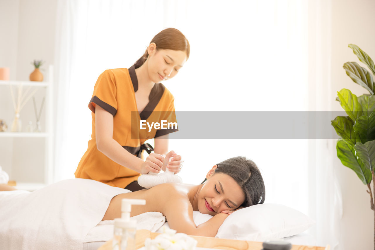 In a spa salon, a young woman enjoys massage therapy.