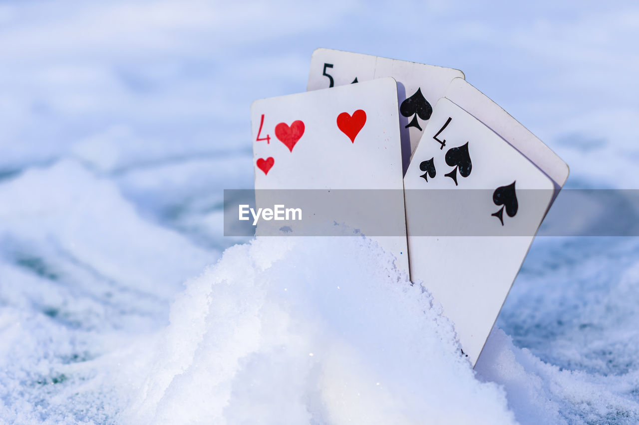 Playing cards stuck in a pile of snow outdoors