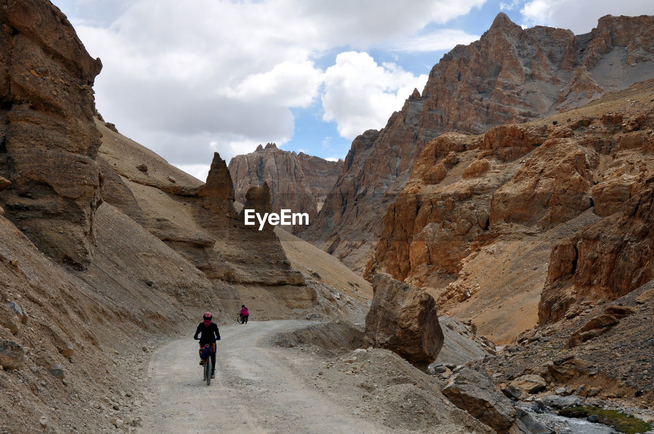 Rear view of people walking on mountain against sky