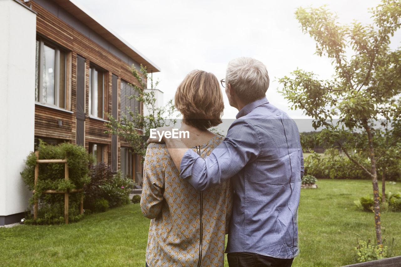 Mature couple in garden looking at house