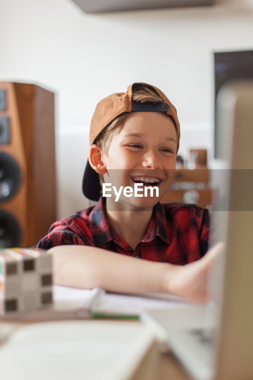 Happy elementary student talking to someone over video call at home.