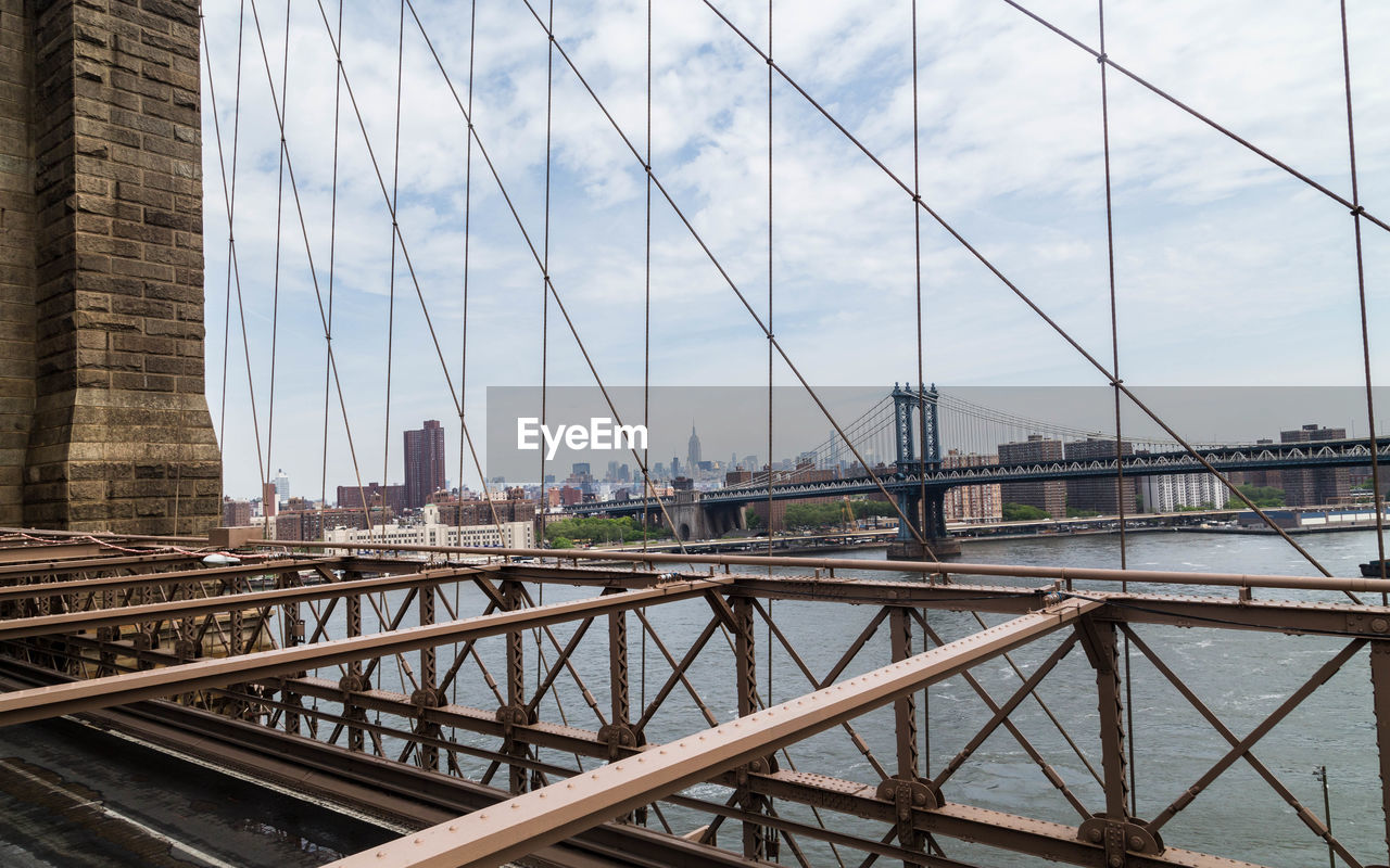 Manhattan bridge over east river against sky seen from brooklyn bridge