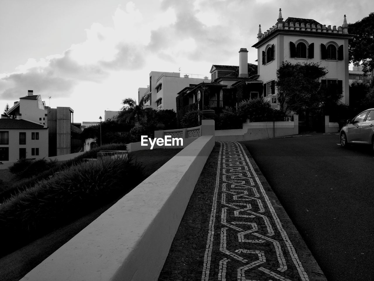 EMPTY ROAD AMIDST BUILDINGS AGAINST SKY