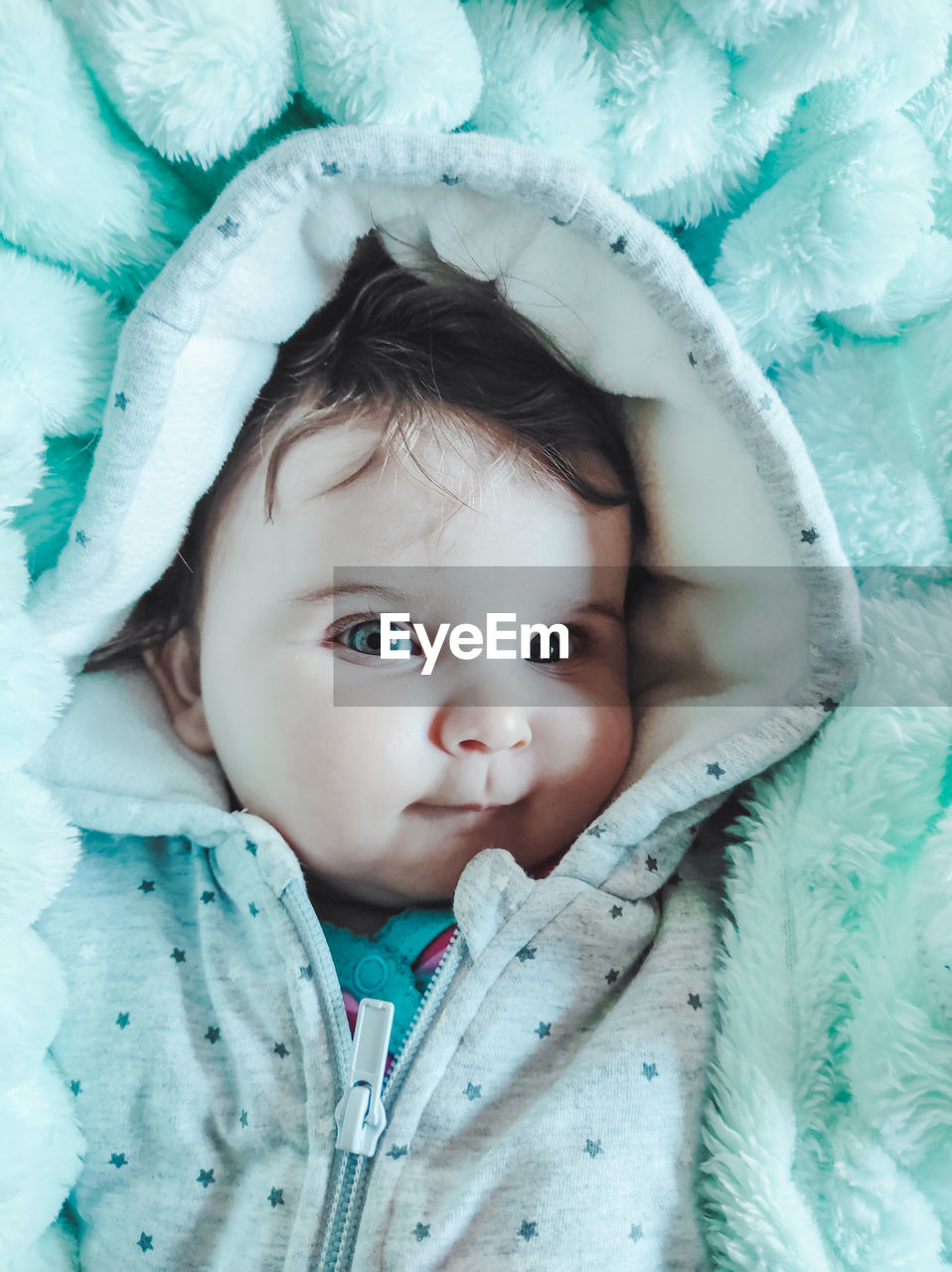 Portrait of cute baby lying on bed wrapped in blanket