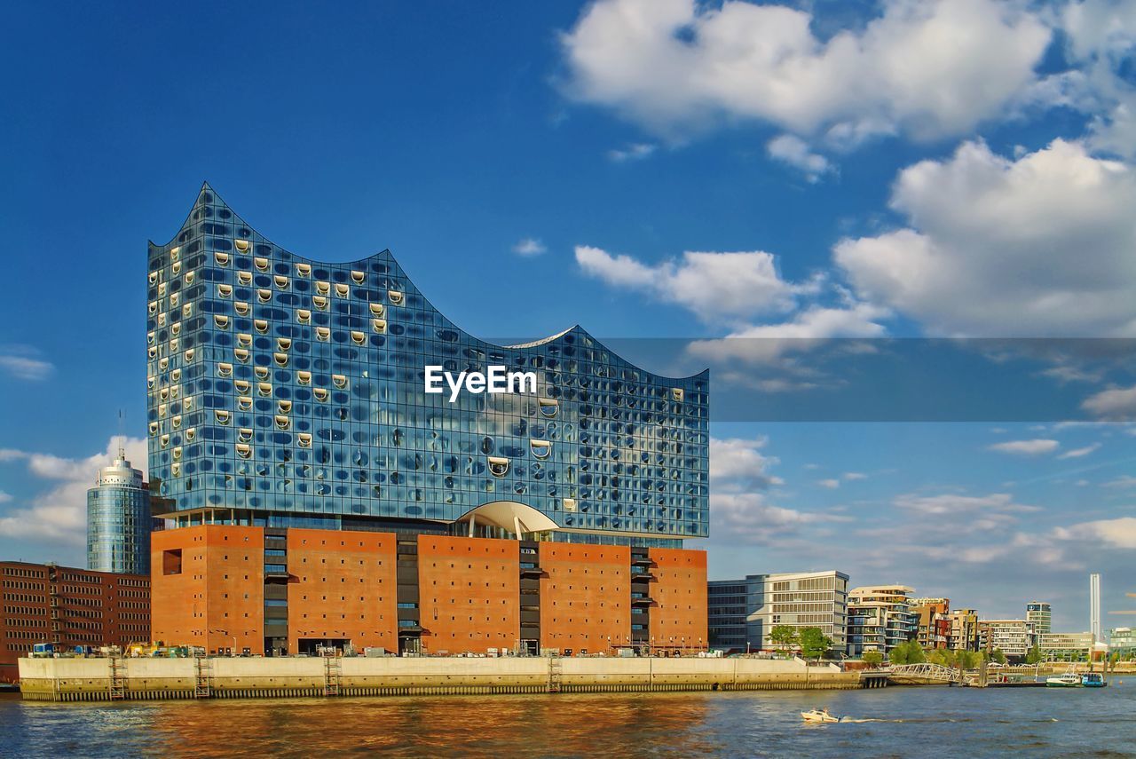 Modern buildings by sea against sky in city