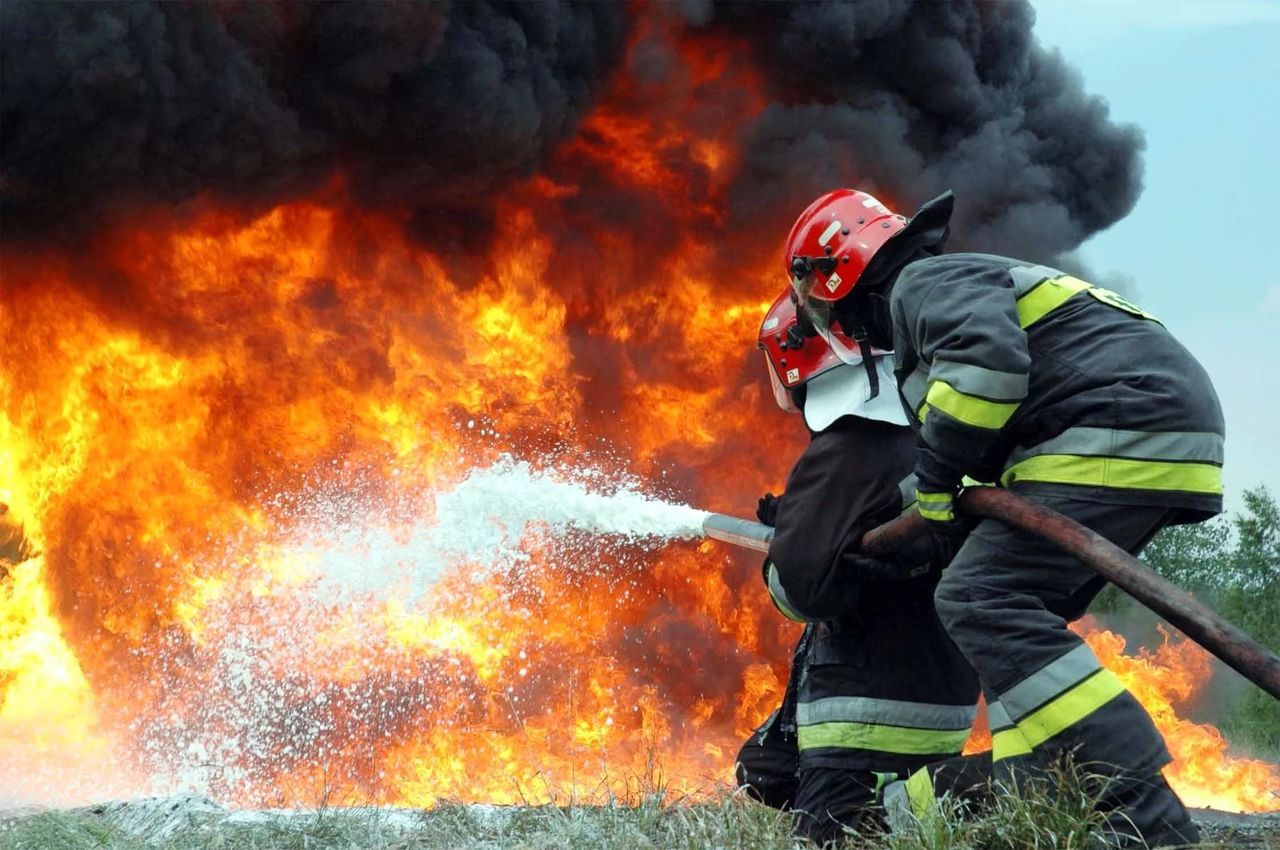 Low angle view of firefighters spraying water on fire