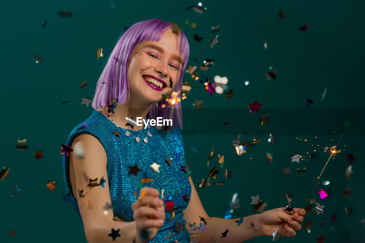 Smiling woman with confetti against colored background