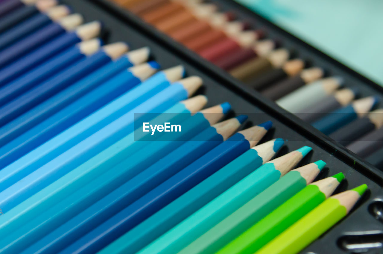 HIGH ANGLE VIEW OF COLORED PENCILS ON TILED FLOOR