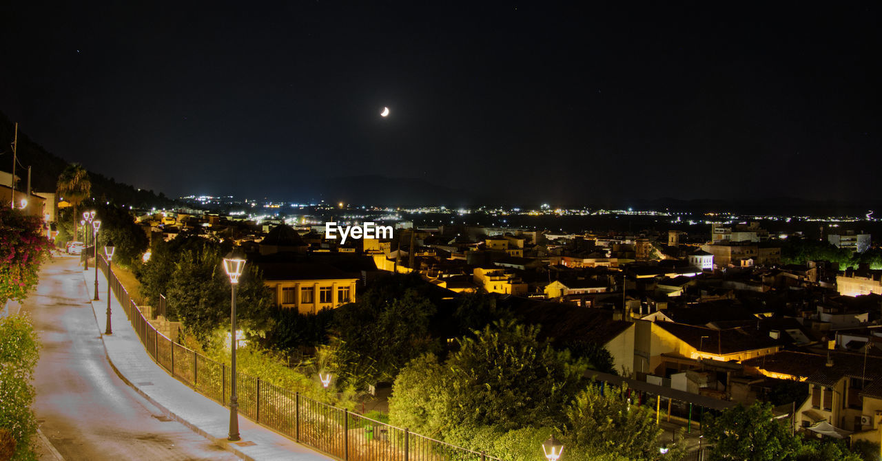 HIGH ANGLE VIEW OF ILLUMINATED CITY BUILDINGS AT NIGHT