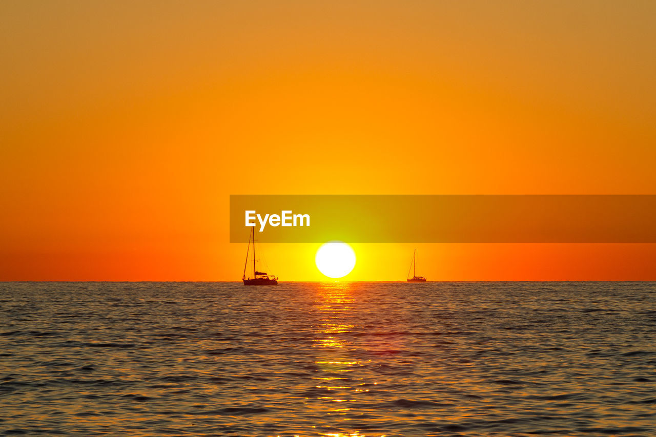 Boat sailing in sea at sunset