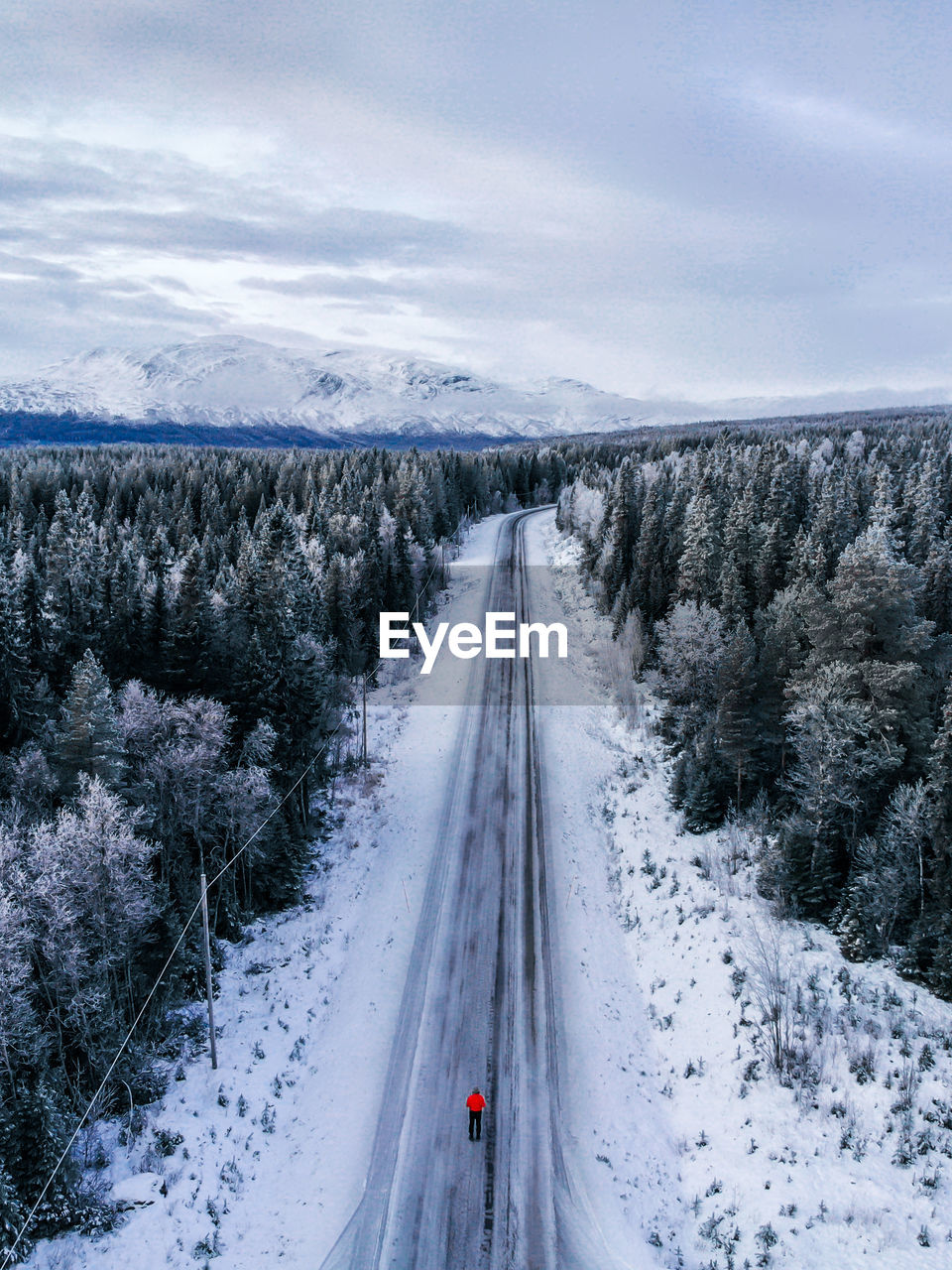 High angle view of man standing on road amidst snow covered landscape against sky