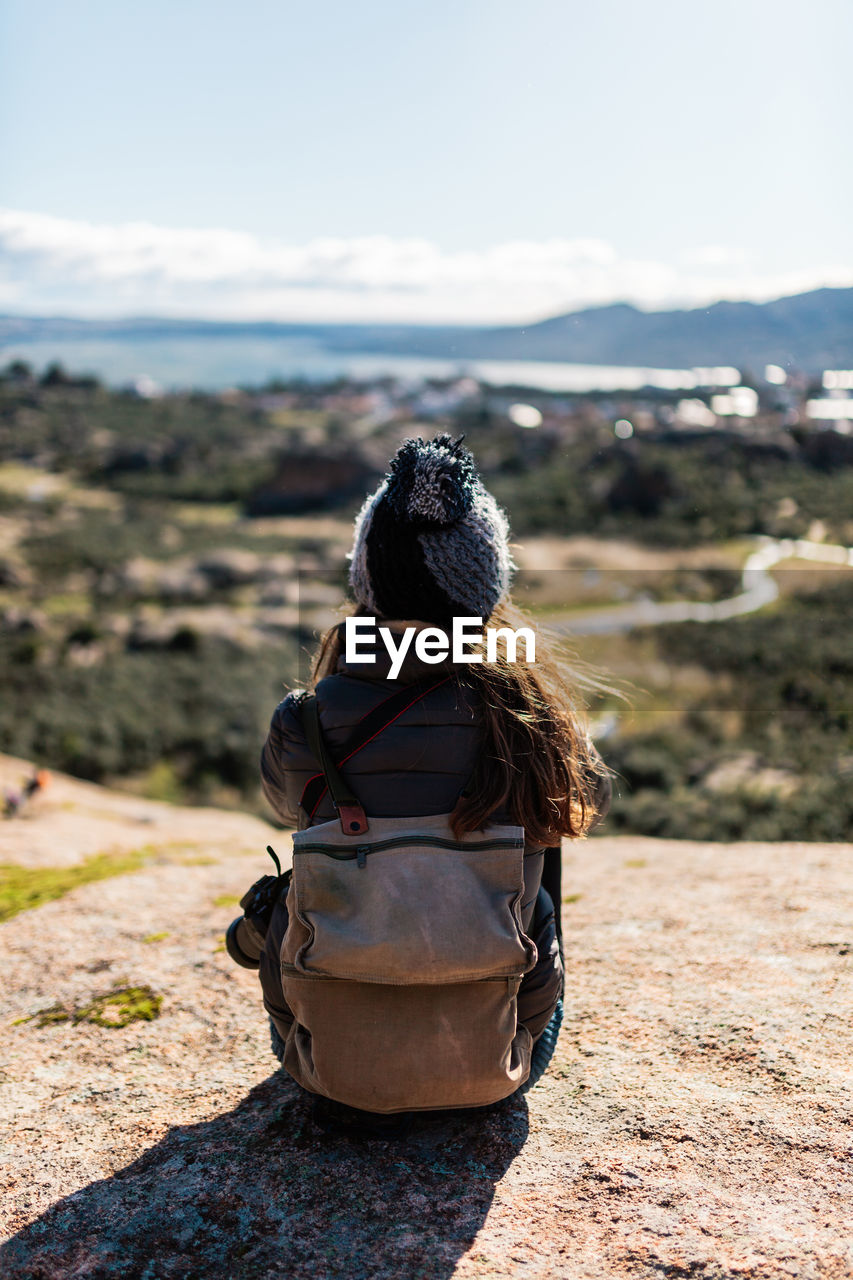 Rear view of woman looking at camera on sunny day