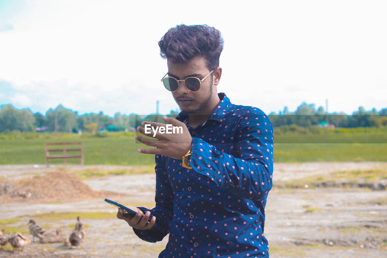 Young man using mobile phone on field