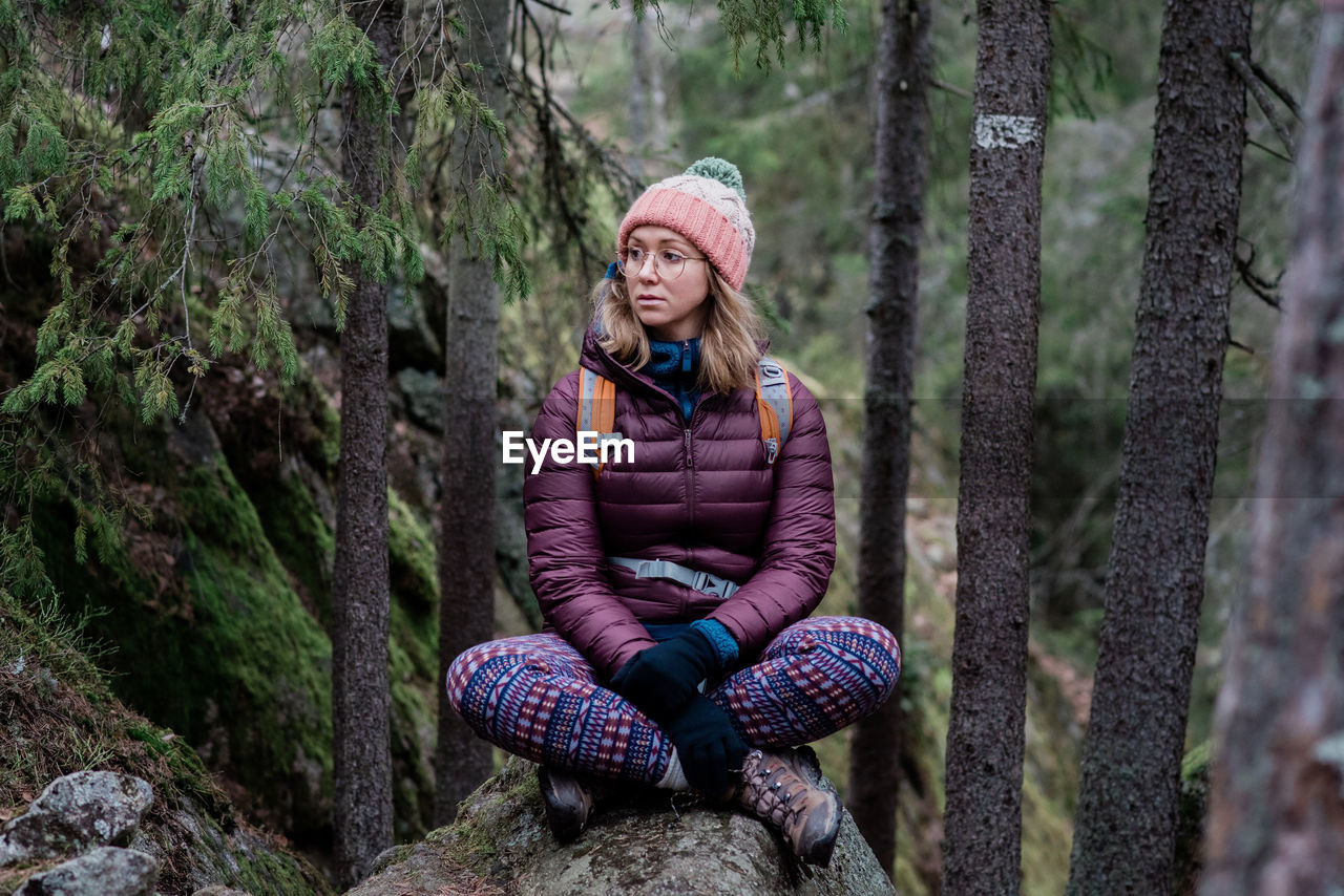 Woman sitting on a rock thinking whilst hiking in the forest in sweden