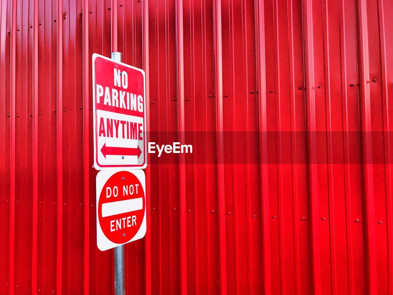 Close-up of no parking sign on red wall