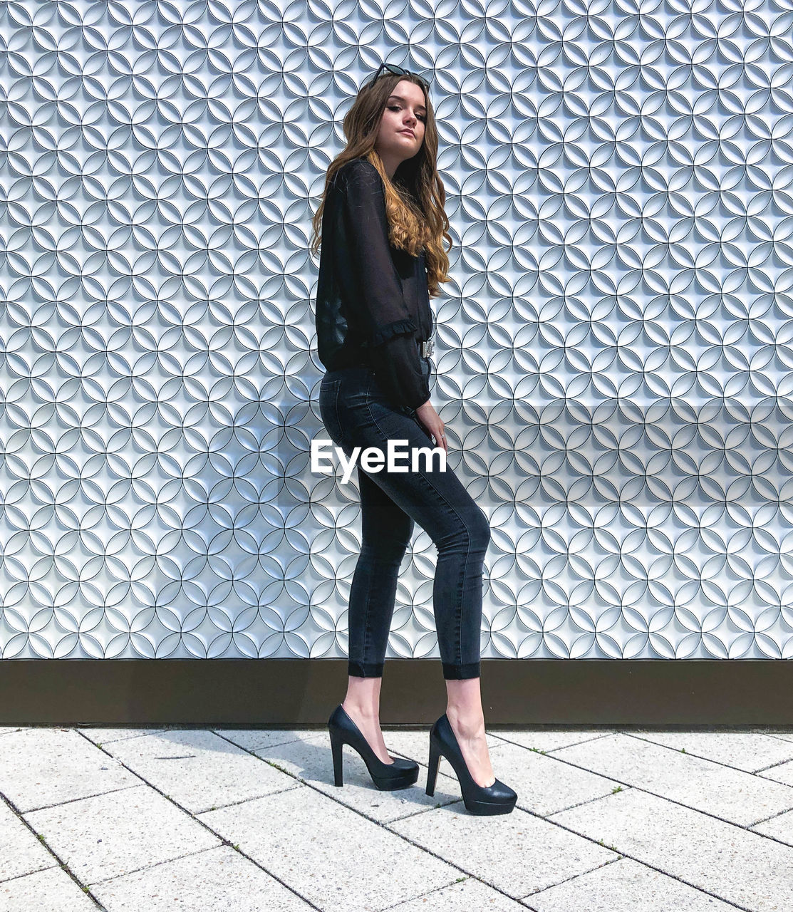 FULL LENGTH PORTRAIT OF WOMAN STANDING AGAINST WALL