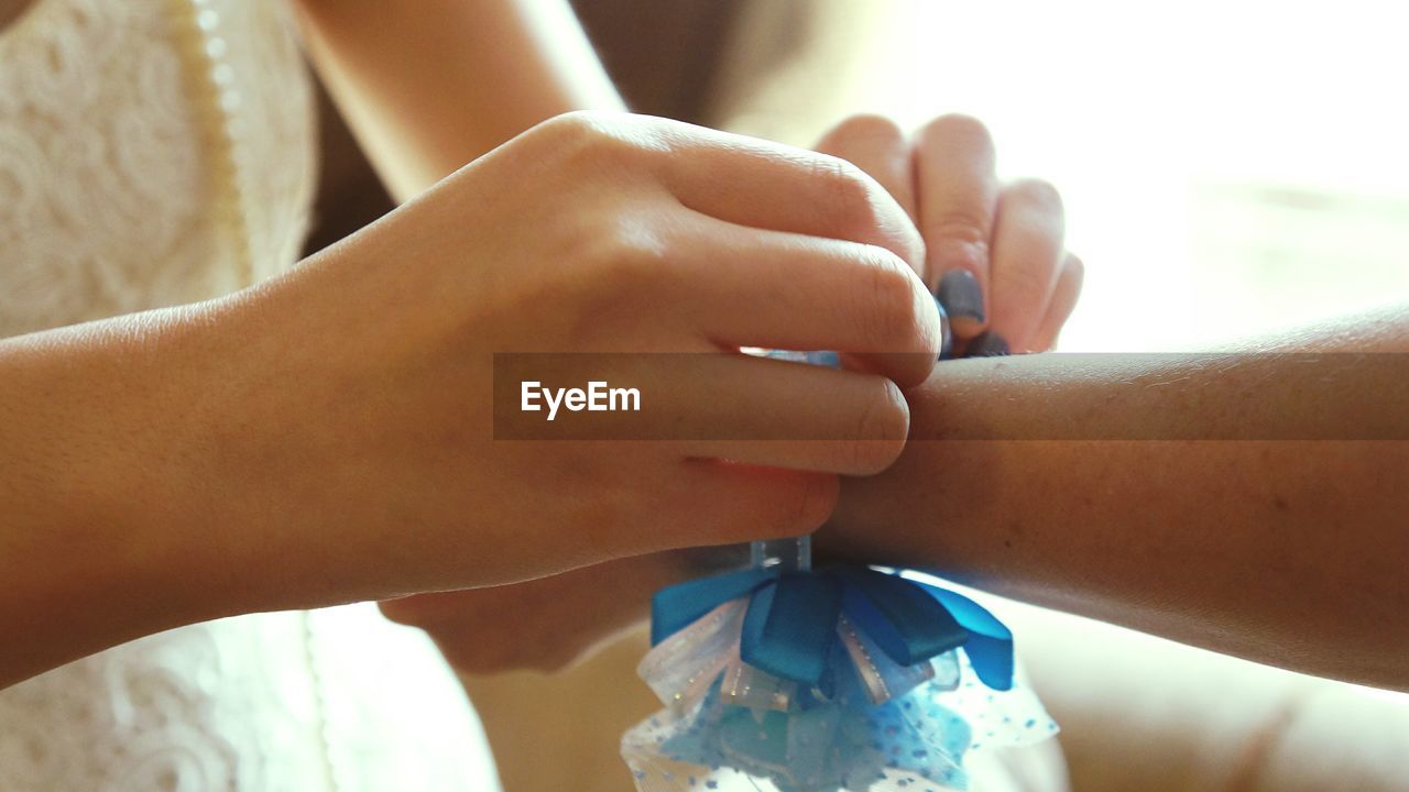 Cropped image of girl tying ribbon of sister hand