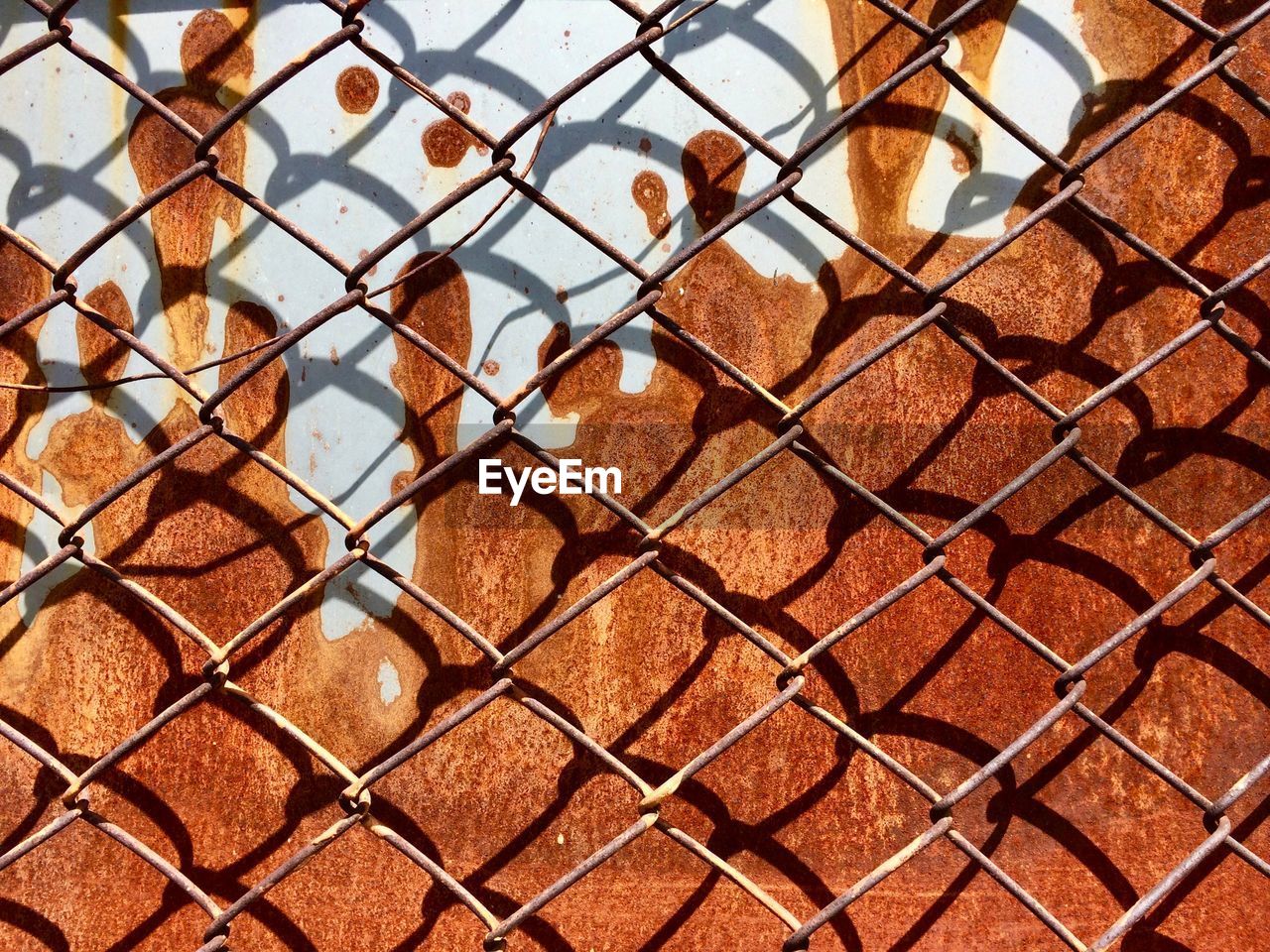 Full frame shot of chainlink fence against rusty wall