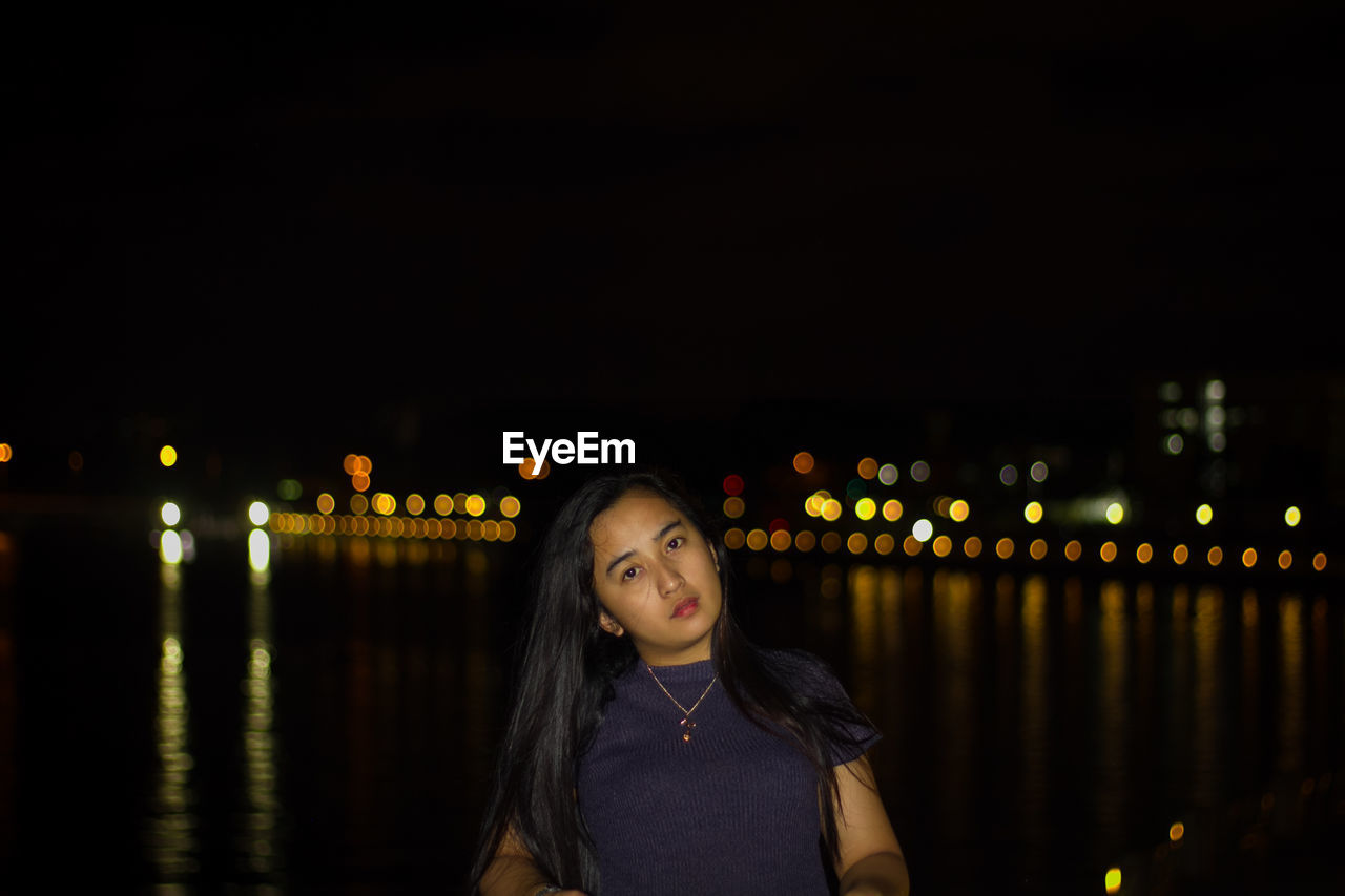 Portrait of young woman looking away at night