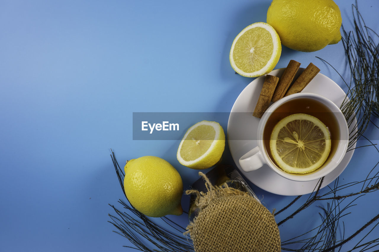 Tea and lemon in a white cup over blue background. copyspace concept.